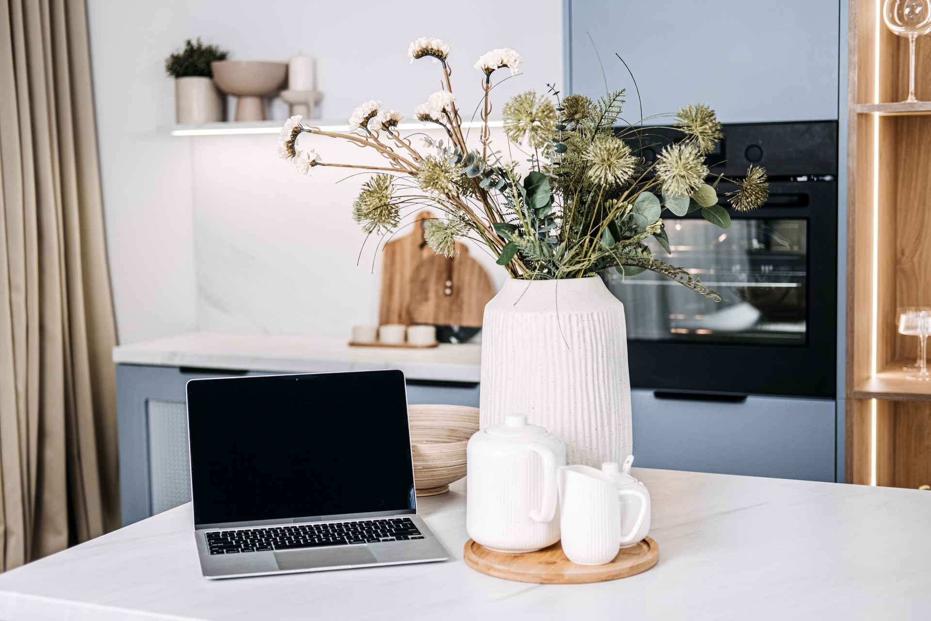 Kitchen Workstation Mockup with Empty Laptop Screen. An elegant kitchen setup with laptop empty screen ready for mockups, surrounded by tasteful home decor and natural light.